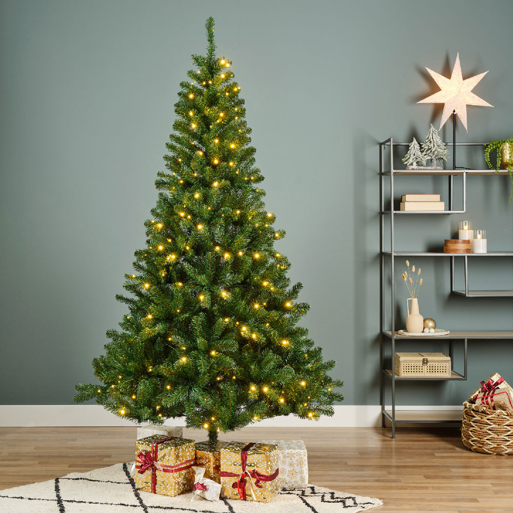 Pre-lit Kielder Pine tree in trendy room with presents underneath